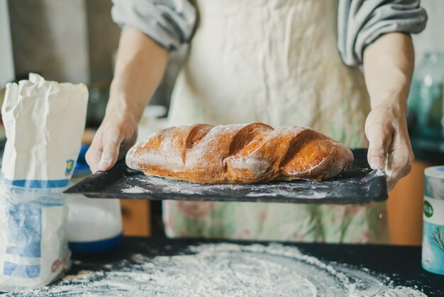 Bäckerhände halten frisch gekochtes langes Brot