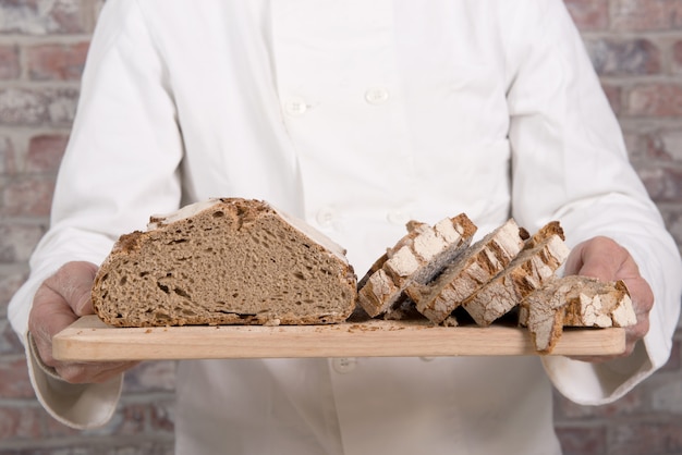 Bäckerhände mit frischem brot auf hölzerner tabelle