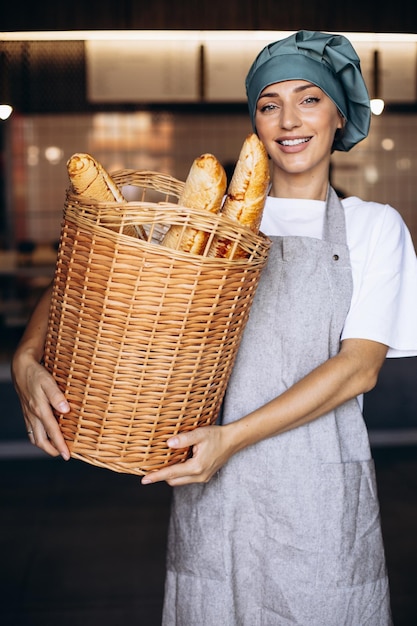 Bäckerin, die einen Korb voller Baguettes hält und lächelt