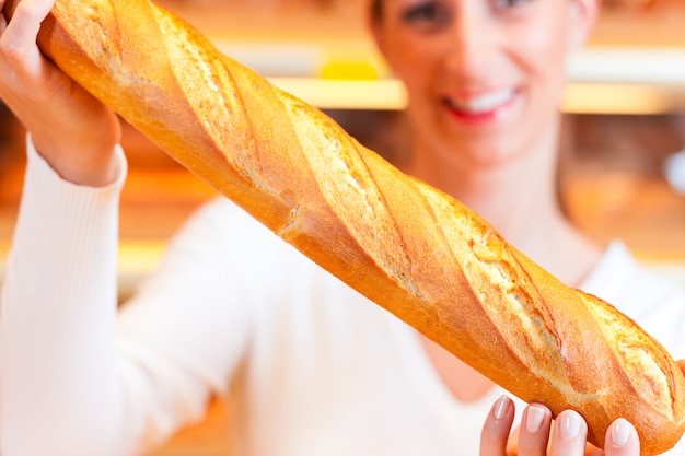 Bäckerin in ihrer Bäckerei mit Baguette