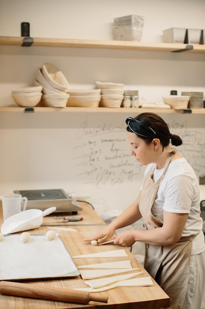 Bäckerin macht Croissants in der Bäckerei, die vor dem Fenster steht