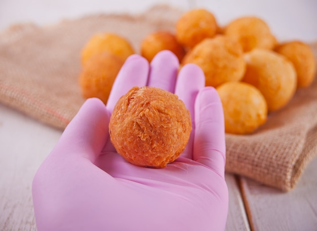 Bällchen der frisch gebackenen selbst gemachten Hüttenkäsekrapfen und der Hand der Frau in den rosa Handschuhen