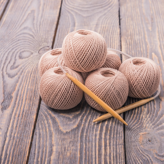 Foto bälle des garns und der stricknadeln für das stricken auf einem hölzernen hintergrund.