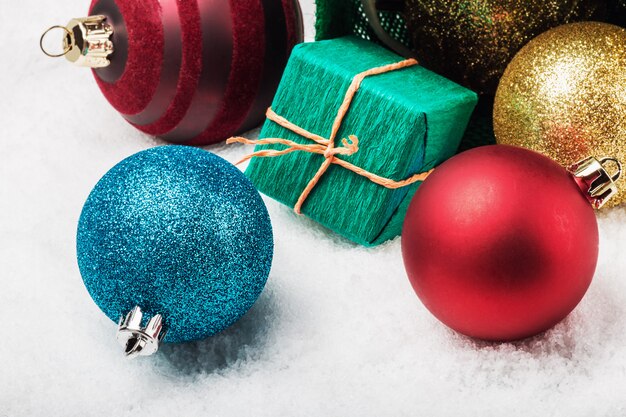 Bälle und Geschenke auf dem Schnee unter dem Weihnachtsbaum