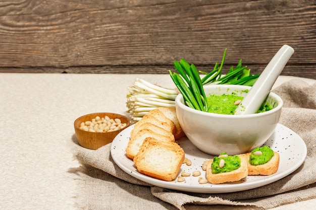 Bärlauch-Pesto mit Olivenöl auf Toast Frische wilde Lauchblätter und Pinienkerne Schale mit duftendem Brotaufstrich