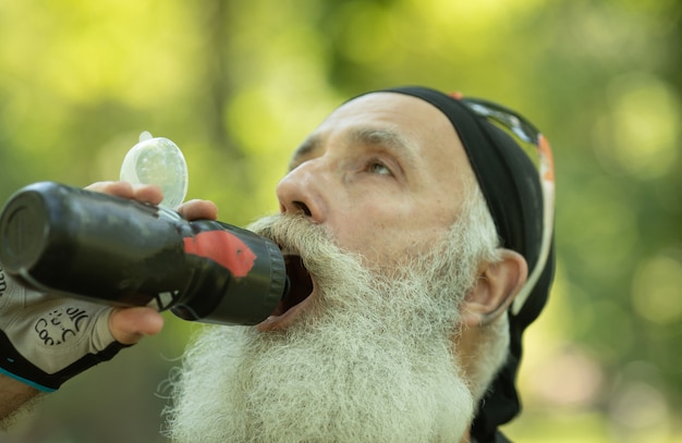 Bärtiger älterer Mann mit einer Flasche Wasser