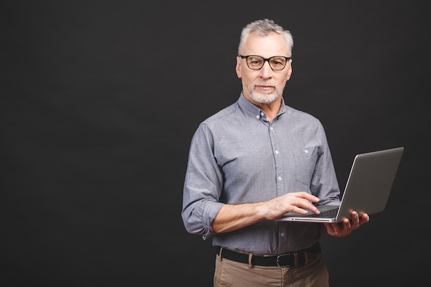 Bärtiger alter Mann des älteren Alters in Brillen, die Laptop-Computer halten und lächeln