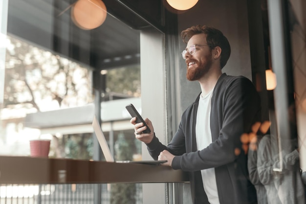 Bärtiger Freiberufler mit Smartphone im Café