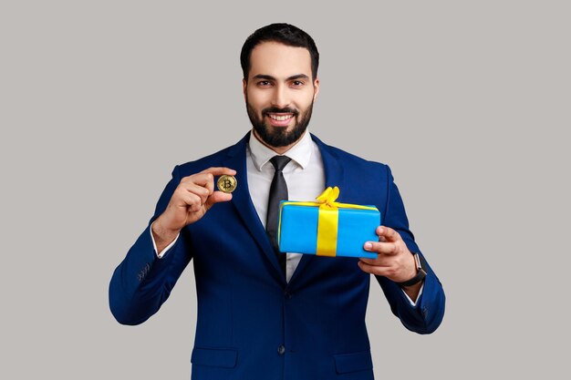 Bärtiger Geschäftsmann, der Geschenkbox und goldene Bitcoin-Kryptowährung als Geschenk hält