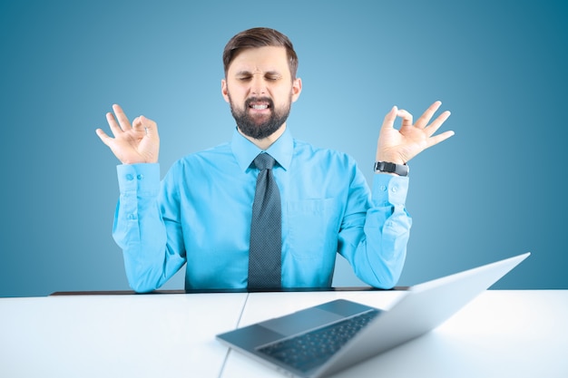 Bärtiger Geschäftsmann meditiert im Büro am Computer