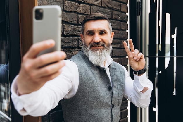 Bärtiger grauhaariger älterer Mann, der ein Selfie macht