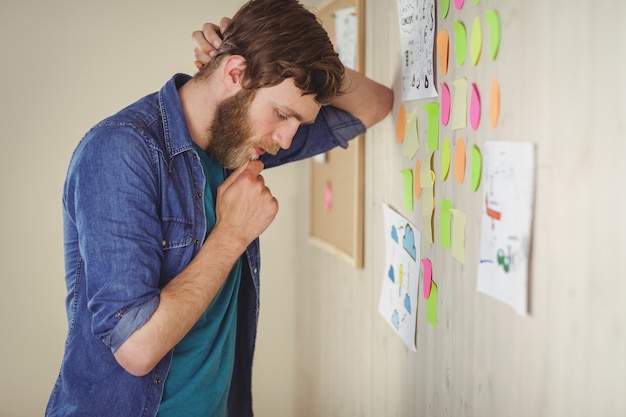 Bärtiger Hippie, der Brainstormingwand betrachtet