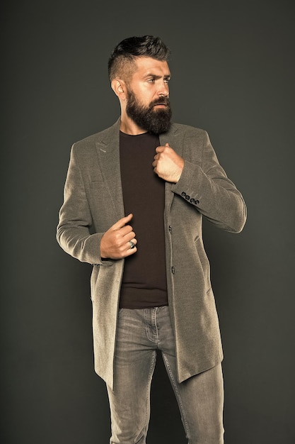 Bärtiger Hipster Hipster auf grauem Hintergrund Bärtiger Hipster trägt Freizeitjacke und Jeans Brutaler Mann im Hipster-Stil