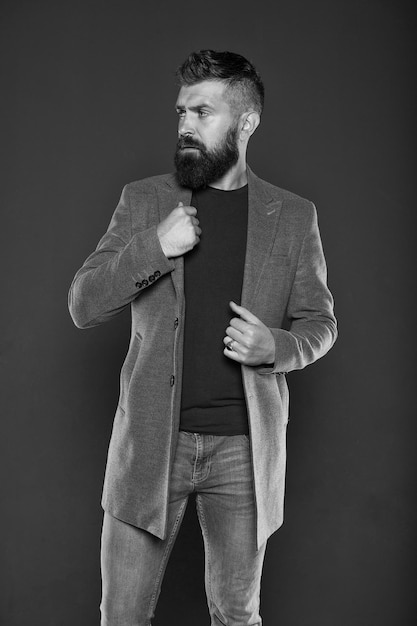 Bärtiger Hipster Hipster auf grauem Hintergrund Bärtiger Hipster trägt Freizeitjacke und Jeans Brutaler Mann im Hipster-Stil