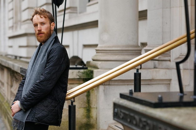 Bärtiger Hipster lehnt mitten in einer Londoner Straße an einem Geländer