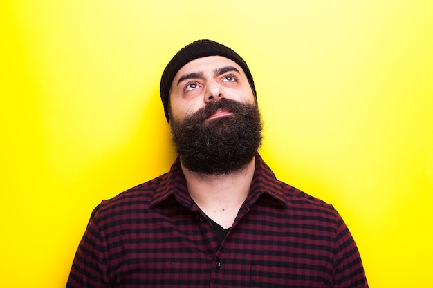 Bärtiger Hipster mit Hut auf gelbem Hintergrund im Studiofoto