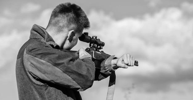 Bärtiger Jäger verbringt die Freizeit mit der Jagd Jagdoptikausrüstung für Profis Brutales männliches Hobby Mann, der auf Zielnaturhintergrund abzielt Zielfähigkeiten Jäger halten Gewehr mit dem Ziel auf mein Ziel