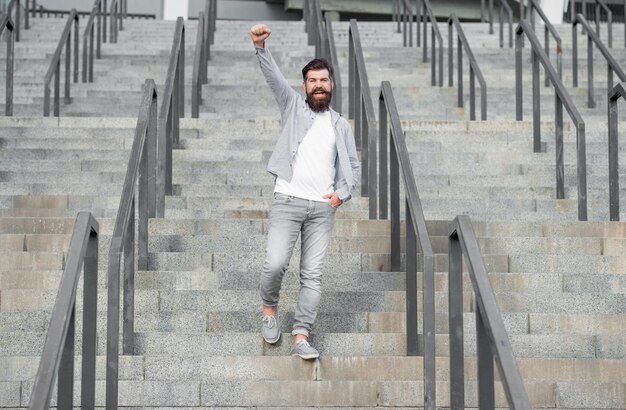 Bärtiger Kerl geht die Treppe hinunter voller Länge von erfolgreichem Kerl mit Bart-Hipster-Kerl im Freien an der Treppe