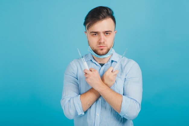 bärtiger männlicher arzt und hält spritze und schreit auf blauem hintergrund