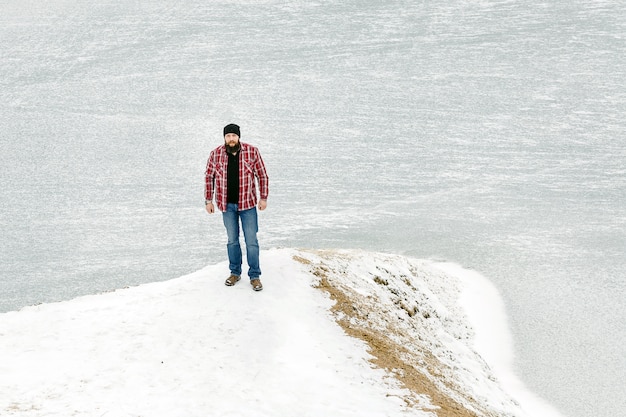 Bärtiger Mann betrachtet einen gefrorenen See im Winter
