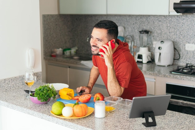 Bärtiger Mann, der am Handy spricht, während er zu Hause das Frühstück zubereitet