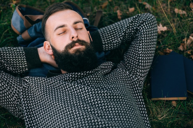 bärtiger Mann, der auf dem Gras liegt, entspannen und Traum, Lebensstilkonzept