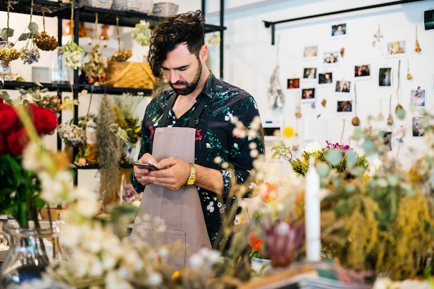 Bärtiger Mann, der Handy im Blumenladen verwendet