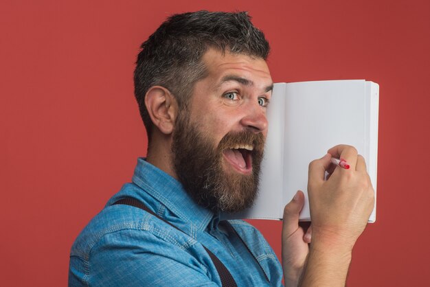 Bärtiger Mann, der mit Stift im Notebook-Bildungskonzept schreibt, fröhlicher Student mit Bart und Schnurrbart