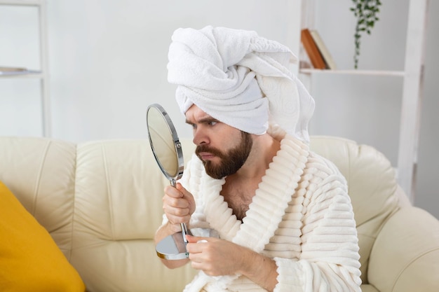 Bärtiger Mann, der seine Gesichtshaut überprüft. Spa-, Körper- und Hautpflege für das männliche Konzept.