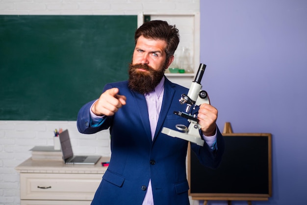 Bärtiger Mann des Lehrers mit Laptopnotizbuch, das Idee hat und Finger auf Sie zeigt. Überraschter Lehrer, der auf Schüler wartet und selbstbewusst lächelt.