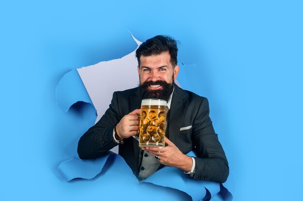 Bärtiger Mann hält Craft-Bier, das durch Papierloch schaut, trinkt Alkohol-Freizeit-Menschen-Konzept