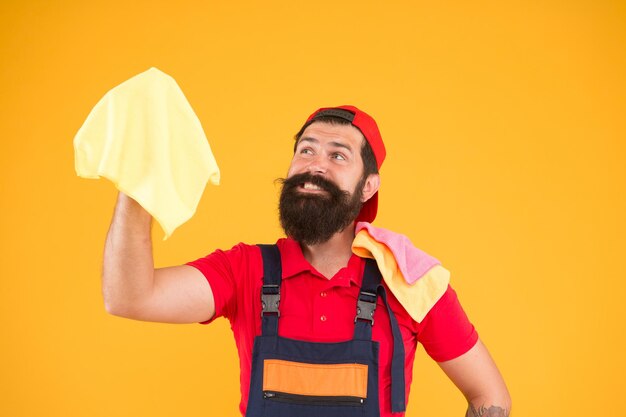 Bärtiger Mann hält Staubtuch Mikrofaser zum Reinigen. Mann sauberes Haus. hauswirtschaftliches Geschäft. Reinigungsdienst rufen. männlicher Dienstmädchenhaushalt. glückliches Hipster-Reinigungsmaterial in der Hand. Arbeiter waschen.