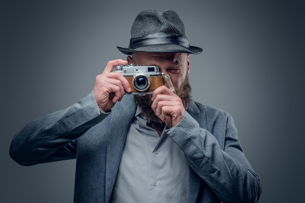 Bärtiger Mann im Filzhut, der mit der alten SLR-Fotokamera schießt.