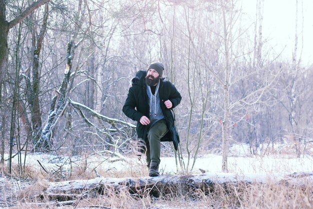 Bärtiger Mann im Winterwald. Attraktiver glücklicher junger Mann mit Bartspaziergang im Park.