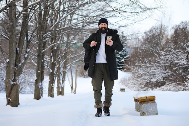 Bärtiger Mann im Winterwald. Attraktiver glücklicher junger Mann mit Bartspaziergang im Park.