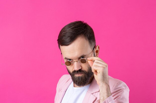 Bärtiger Mann in rosa Jacke mit Brille Emotionales Studioporträt