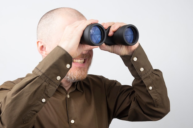 Bärtiger Mann mit Fernglas in den Händen, der glücklich in die Ferne schaut