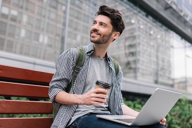 Bärtiger Mann mit Laptop, Planungsprojekt, Kaffeetrinken. Hipster Student, der draußen studiert