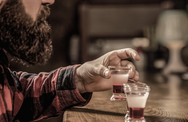 Bärtiger Mann Schüsse Cocktail Tequila Schüsse Wodkawhisky Rum Barkeeper im Pub Tequila erschossen Bunte Cocktails an der Bar