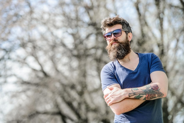 Bärtiger Mann trägt moderne modische Sonnenbrille UV-Filter Mann mit Sonnenbrille Naturhintergrund Bärtiger Hipster brutaler Mann trägt schützende Sonnenbrille Hipster zuversichtlich in dunkle Sonnenbrille