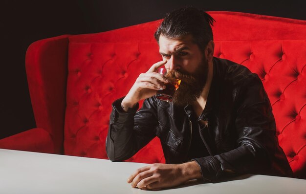 Bärtiger Mann trinkt Whiskey Whiskey oder Cognac Brandy Hipster brutaler Mann Trinker Alkoholiker mit Alkohol