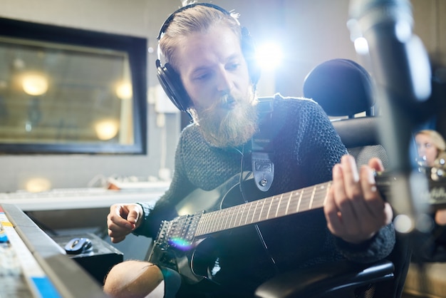 Foto bärtiger musiker mit gitarre im tonstudio