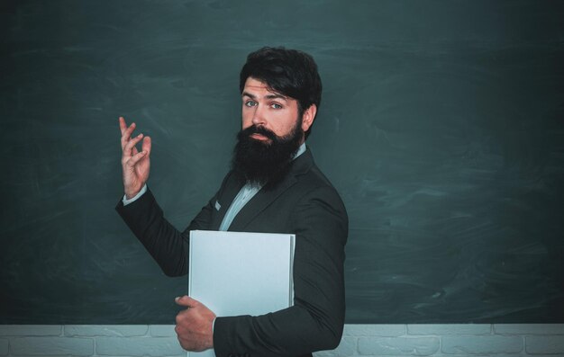 Bärtiger professor beim schulunterricht an schreibtischen im klassenzimmer zurück zur schule und glückliche zeit high school c