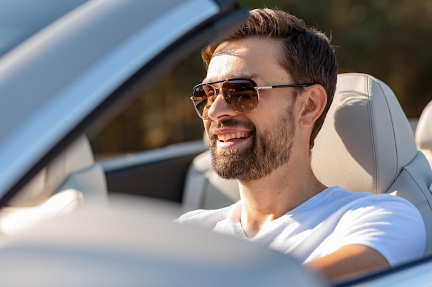 Bärtiger Typ mit Sonnenbrille, der Cabriolet fährt