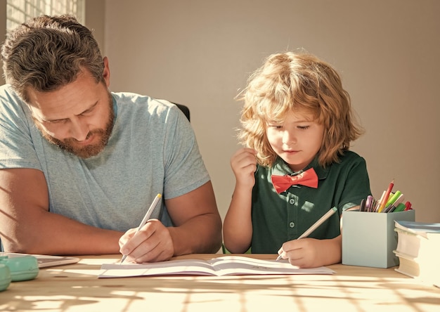 Foto bärtiger vater schreibt schulhausaufgaben mit seinem kleinen sohn im klassenzimmer