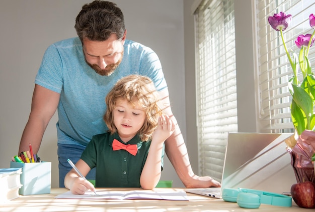 Bärtiger Vater schreibt Schulhausaufgaben mit seinem kleinen Sohn in Elternschaft im Klassenzimmer