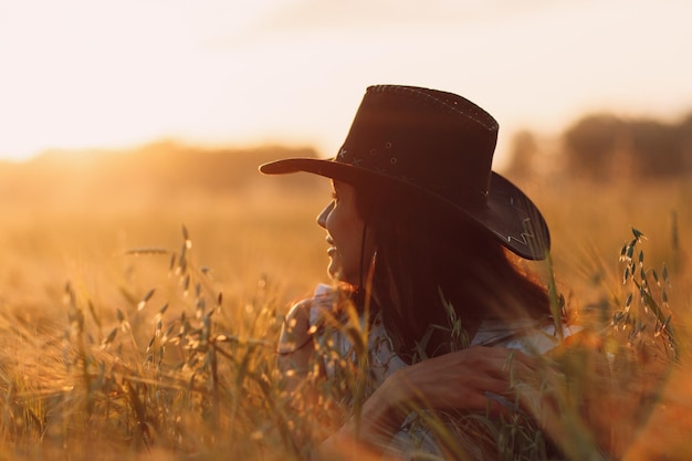 Bäuerin mit Cowboyhut auf dem landwirtschaftlichen Feld bei Sonnenuntergang