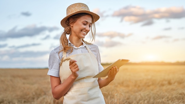 Bäuerin Strohhut Smart Farming stehendes Ackerland lächelnd mit digitaler Tablette Agronomin Spezialistin Forschung Überwachung Analyse Daten Agrobusiness