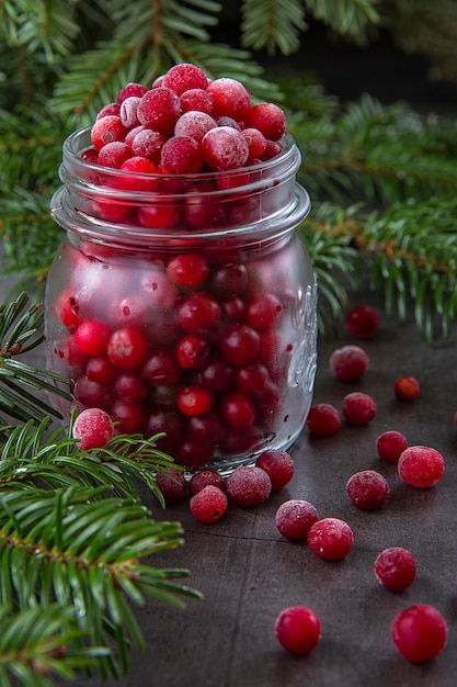 Baga de amora congelada em uma jarra na mesa decorada com galhos da árvore de Natal. Natal inverno