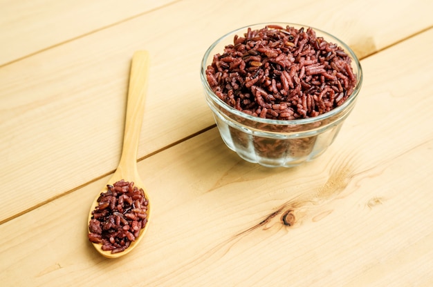 Baga de arroz em uma colher e tigela sobre uma mesa de madeira.